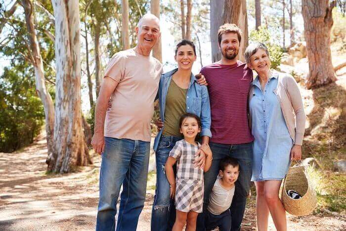 3 generation family smiling while hiking through the woods